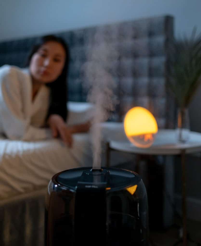 UV humidifier blowing vapor into the air next to a bed