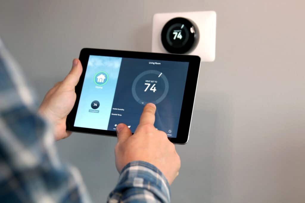 Man is adjusting the temperature using a tablet with smart home app in modern living room